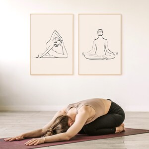 May include: Two black and white line drawings of people in yoga poses. The first drawing shows a person in a seated pose with their legs crossed. The second drawing shows a person in a forward bend pose. The drawings are framed and hanging on a white wall.