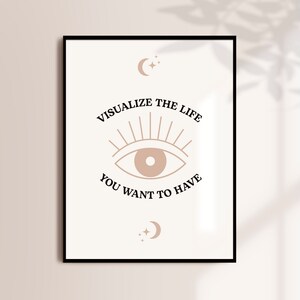 Peut inclure: Une affiche imprimable avec un œil stylisé et le texte "Visualisez la vie que vous voulez avoir". L'affiche est encadrée en noir et a un fond blanc avec un œil et un texte brun clair.