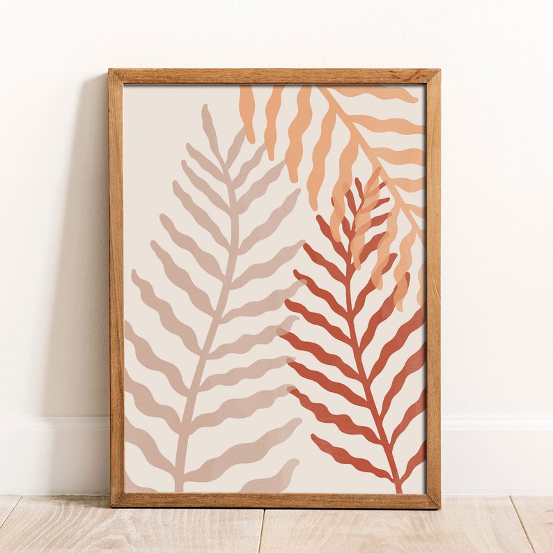 May include: A framed print with a minimalist design featuring two stylized fern leaves in shades of peach, pink, and red on a cream background.