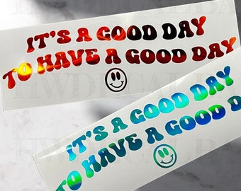 May include: Two rectangular stickers with the text "IT'S A GOOD DAY TO HAVE A GOOD DAY" and a smiley face. One sticker has red, orange, and black text. The other has blue and green text.