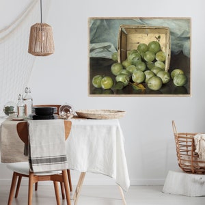 Op de afbeelding: Een schilderij van een houten mand vol groene pruimen. De pruimen zijn in een stillevencompositie op een donkere achtergrond gerangschikt.