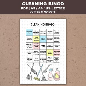 May include: A printable cleaning bingo card with a colourful design. The card has a grid of 5x5 squares with cleaning tasks listed in each square. The centre square says "FREE". The card is surrounded by a black border.