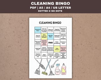 May include: A printable cleaning bingo card with a colorful design. The card has a grid of 5x5 squares with cleaning tasks listed in each square. The center square says "FREE". The card is surrounded by a black border.