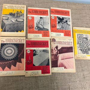 May include: A collection of seven vintage The Workbasket magazines featuring various cover illustrations of home crafts, including table settings, crochet patterns, and bedding, with printed text detailing volume numbers, dates, and prices.