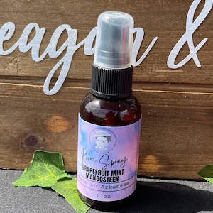 May include: A 2 ounce bottle of room spray with a pink, blue, and white label. The label says "Room Spray Grapefruit Mint Mangosteen Made in Arkansas".