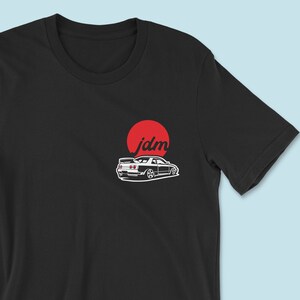 May include: Black t-shirt with a white silhouette of a car and the word "jdm" in a red circle.