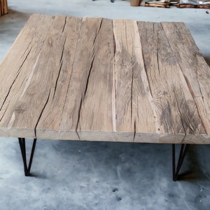Può includere: Un tavolino da caffè in legno rustico con una finitura in legno naturale e un piano rettangolare. Il tavolo ha quattro gambe a forcina nere.