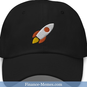 May include: A black baseball cap with an embroidered rocket ship design in orange, white, and gray. The rocket ship is facing to the right.