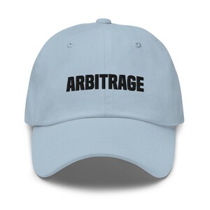 May include: A light blue baseball cap with the word "ARBITRAGE" embroidered in black on the front.