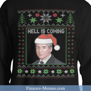 May include: Black sweatshirt with a Christmas sweater design. The design includes a portrait of a man wearing a Santa hat, with the text "HELL IS COMING". The sweater has a festive pattern with snowflakes, trees, and stars.