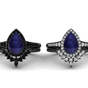 May include: Two black wedding ring sets. Each set features a pear-shaped, blue-speckled stone. One ring is surrounded by black stones, the other by white stones. The bands are black and have additional stones.