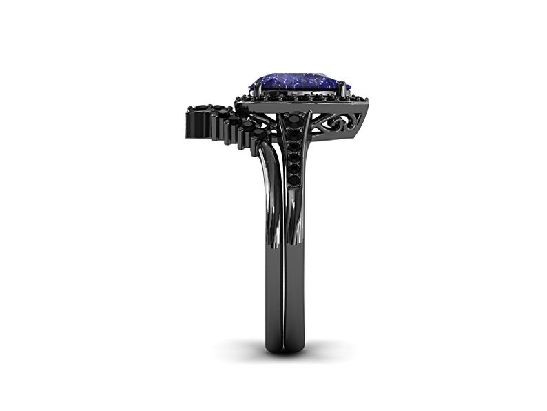 May include: A black ring with a large, rectangular, blue gemstone as the focal point. The ring features a halo of smaller black stones around the main gem and a decorative design on the band. The ring is set against a white background.