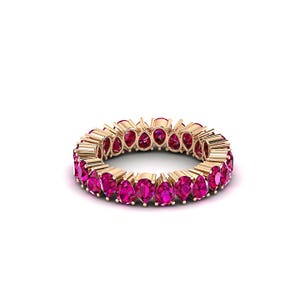 May include: A gold ring featuring a continuous row of vibrant, pear-shaped, pink gemstones. The ring's band is a warm gold color, and the gemstones are set closely together, creating a full circle of color against a white background.