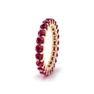 Peut inclure: Une bague en or avec une rangée d'éternité complète de pierres précieuses rouge rubis.