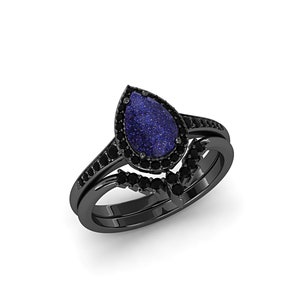 May include: A black ring set featuring a pear-shaped blue gemstone with a sparkling appearance, surrounded by small black stones. The set includes a matching band with additional black stones, creating a cohesive and elegant design.