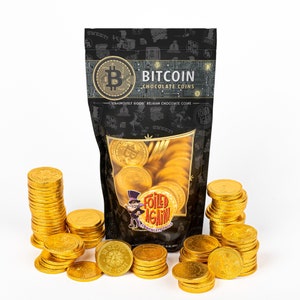 May include: A bag of gold foil-wrapped chocolate coins with the text "Bitcoin Chocolate Coins" and "Foiled Again!" on the front. The bag is sitting on a white surface with a pile of gold chocolate coins in front of it.