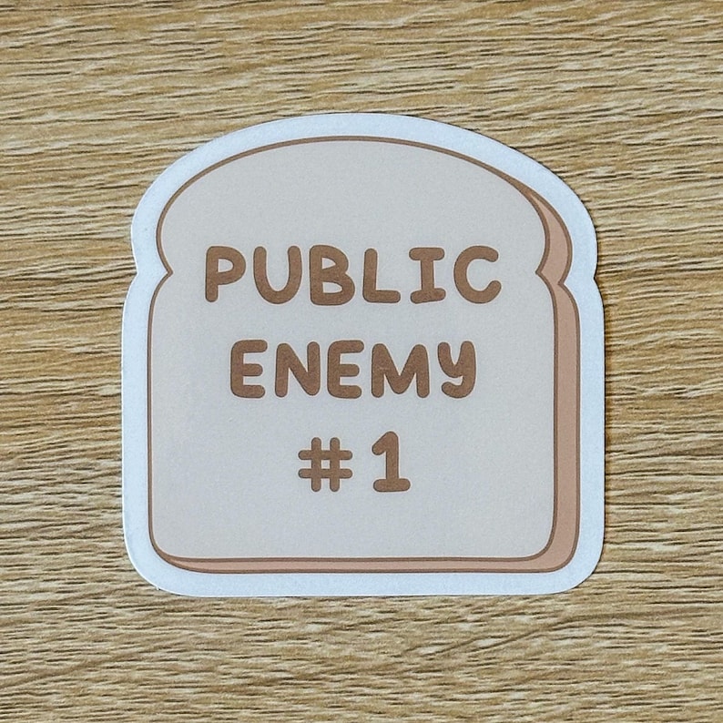 May include: A white sticker shaped like a slice of bread with the text "PUBLIC ENEMY #1" in brown lettering.