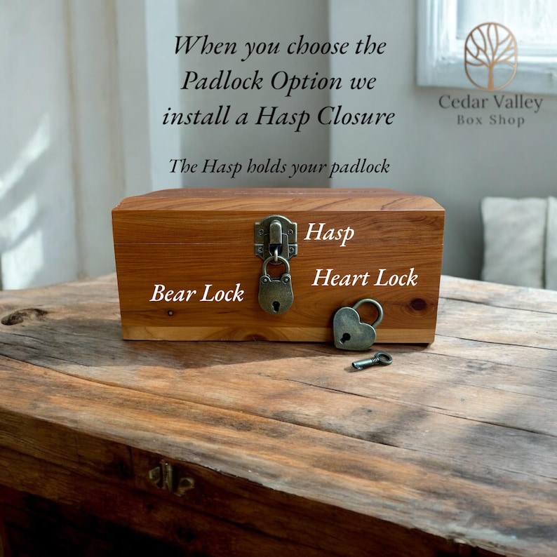 May include: A wooden box with a hasp closure and two locks. The box is labelled "Bear Lock" and "Heart Lock". The text "When you choose the Padlock Option we install a Hasp Closure" and "The Hasp holds your padlock" is visible above the box. The text "Cedar Valley Box Shop" is visible in the top right corner of the image.