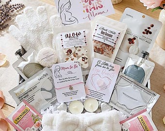 May include: A gift basket filled with self-care items for a new mother. The basket includes a white headband, gloves, tea bags, eye masks, bath salts, and a card that says "You got this Mama". Pink rose petals and a bouquet of pink flowers are also present.