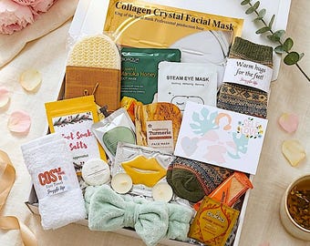 Könnte beinhalten: Eine Geschenkbox mit Pflegeprodukten, darunter Gesichtsmasken, Socken und Badesalze. Die Box enthält eine Kollagen-Gesichtsmaske, eine Kurkuma-Gesichtsmaske und Socken mit dem Text "Warm hugs for the feet!". Außerdem ein Stirnband und ein kleines Handtuch.