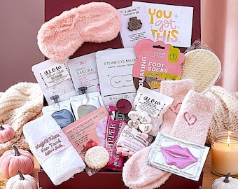 Può includere: Una confezione regalo contenente una mascherina per dormire in pelliccia sintetica rosa, un asciugamano bianco, calzini rosa soffici, calzini esfolianti al cocco, una maschera vapore per occhi, polvere da bagno, una maschera labbra e una candela.