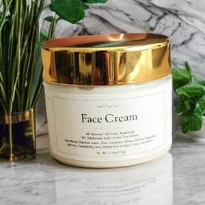 May include: A gold jar of face cream with a white label that reads "Face Cream" and lists the ingredients: Distilled water, Aloe vera Juice, Mango butter, Vegetable glycerin, Emulsifying wax, Hyaluronic acid gel, Green tea extract.  Net Wt. 2.54oz(72g).