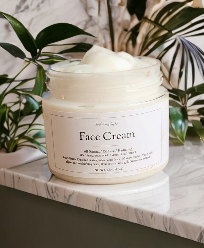 May include: A white jar of face cream with a white label that reads "Face Cream" and lists the ingredients: "All Natural/Oil Free/Hydrating W/Hyaluronic acid | Green Tea Extract Ingredients: Distilled water, Aloe vera juice, Mango butter, Vegetable glycerin, Emulsifying wax, Hyaluronic acid gel, Green tea extract Net. Wt. 2.54oz(72g)"