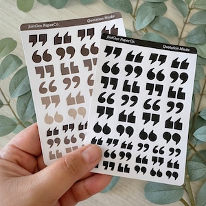 May include: Two sheets of sticker paper with quotation marks in various sizes and shades of grey and black. The text "JustGee PaperCo." and "Quotation Marks" is printed on each sheet.