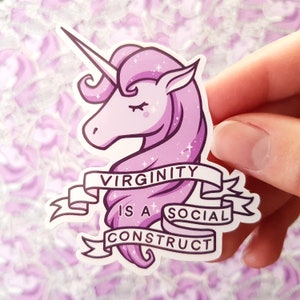 May include: A sticker featuring a pink unicorn with a white horn and closed eyes. The sticker has the text "VIRGINITY IS A SOCIAL CONSTRUCT" on a banner. The unicorn has a sparkly design.