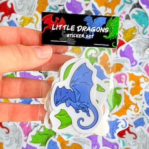 Könnte beinhalten: Ein klarer Plastikbeutel enthält ein Set bunter Drachenaufkleber. Die Aufkleber zeigen Drachendesigns in Rot, Blau, Grün, Lila und Orange. Der Beutel trägt die Aufschrift "Little Dragons Sticker Set".