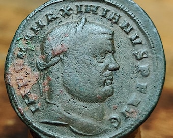 May include: A weathered bronze coin featuring a profile of a man with a beard and laurel wreath. The coin's surface shows signs of age and wear, with visible text around the edges. The coin is a historical artifact.