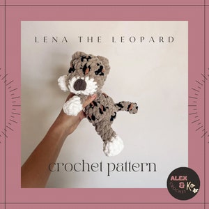 May include: Crochet pattern for a plush leopard toy named Lena. The toy is brown and black with white accents. The pattern is available for purchase from Alex & Ko Crochet.