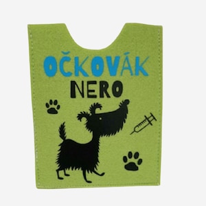 Könnte beinhalten: Ein hellgrüner Filz-Impfausweishalter für Haustiere mit dem Text "OČKOVÁK NERO" in Blau und Schwarz. Ein schwarzer Cartoon-Hund, Pfotenabdrücke und eine Spritze sind ebenfalls auf dem Halter abgebildet.