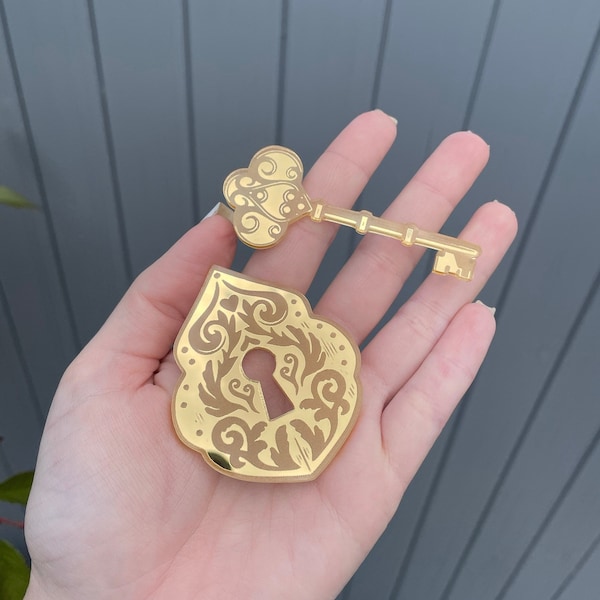 Peut inclure: Un ensemble clé et serrure de couleur or avec des motifs floraux ornés. La clé a une tête en forme de trèfle et la serrure a un trou de serrure. L'ensemble est probablement un objet décoratif ou fait partie d'un design plus large.