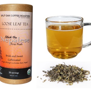 May include: A brown cardboard tube with a label that reads "Split Oak Coffee Roasters Loose Leaf Tea Black Tea Nepalese First Flush Brisk and Sweet Caffeinated Origin: Shangri-La Estate, Ilam, Nepal 20 servings Net wt. 1.2 oz"  The tube contains loose leaf tea. A glass mug filled with brewed tea and a pile of loose leaf tea are also shown.