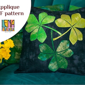 May include: A cushion with a dark background featuring a green and gold shamrock design. The cushion has a quilted texture and is part of a PDF pattern. The text "Applique PDF pattern" is visible.
