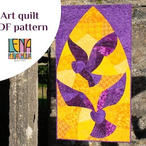 May include: A purple and yellow art quilt with a design of two stylized doves. The quilt is hanging on a stone wall. The text "Lena Pugachova Quilt Art" is in the lower left corner.