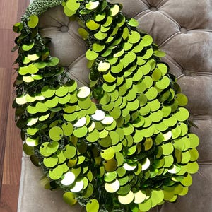 May include: A lime green sequined handbag with a crocheted handle.