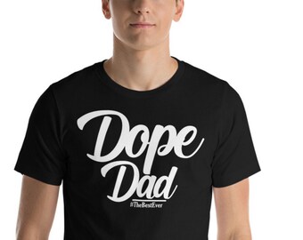 Peut inclure: Un t-shirt noir avec du texte blanc qui dit "Dope Dad #TheBestEver".