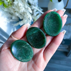 May include: Three smooth, green jade palm stones. The stones are oval shaped and have a polished, glossy finish.