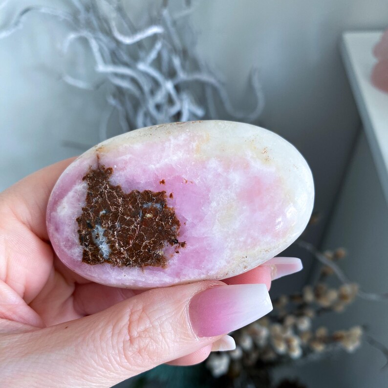Hand holding a pink and brown stone with a blurred background
