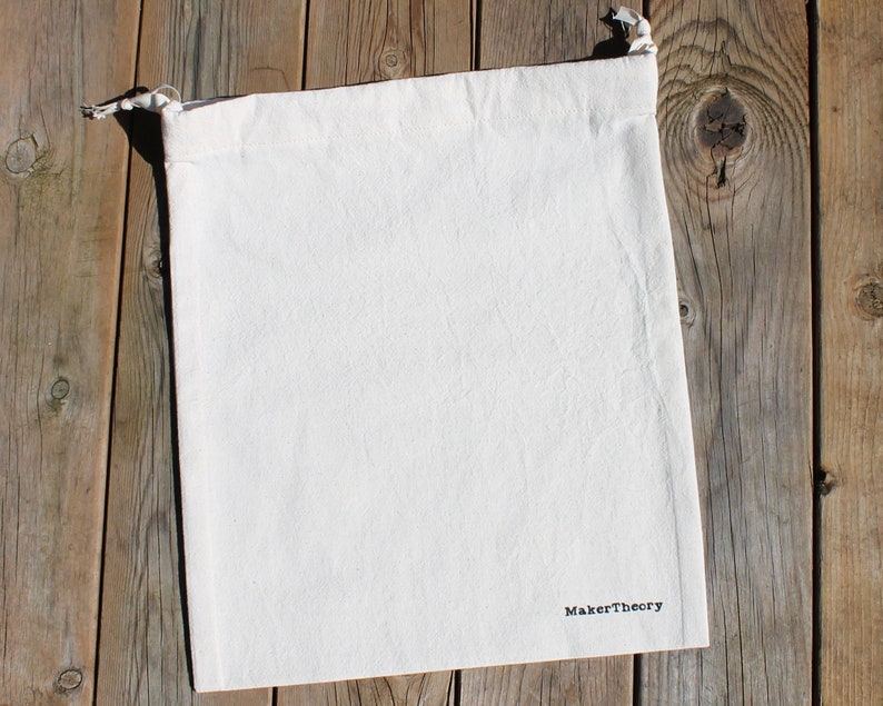May include: A white cotton drawstring bag with the text "MakerTheory" printed in black on the bottom.