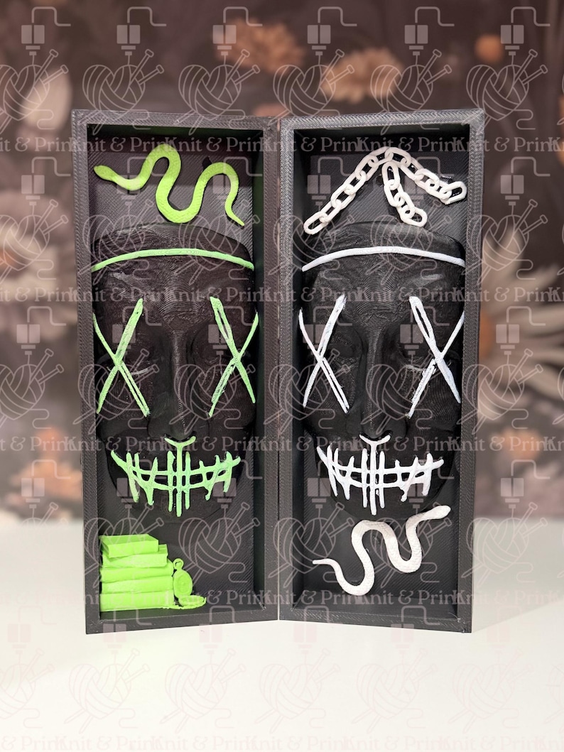 May include: Two black skull masks with white and neon green accents, displayed in a black box. The masks have an X-shaped design over the eyes and a stitched mouth. The box contains a neon green snake and other decorative elements.