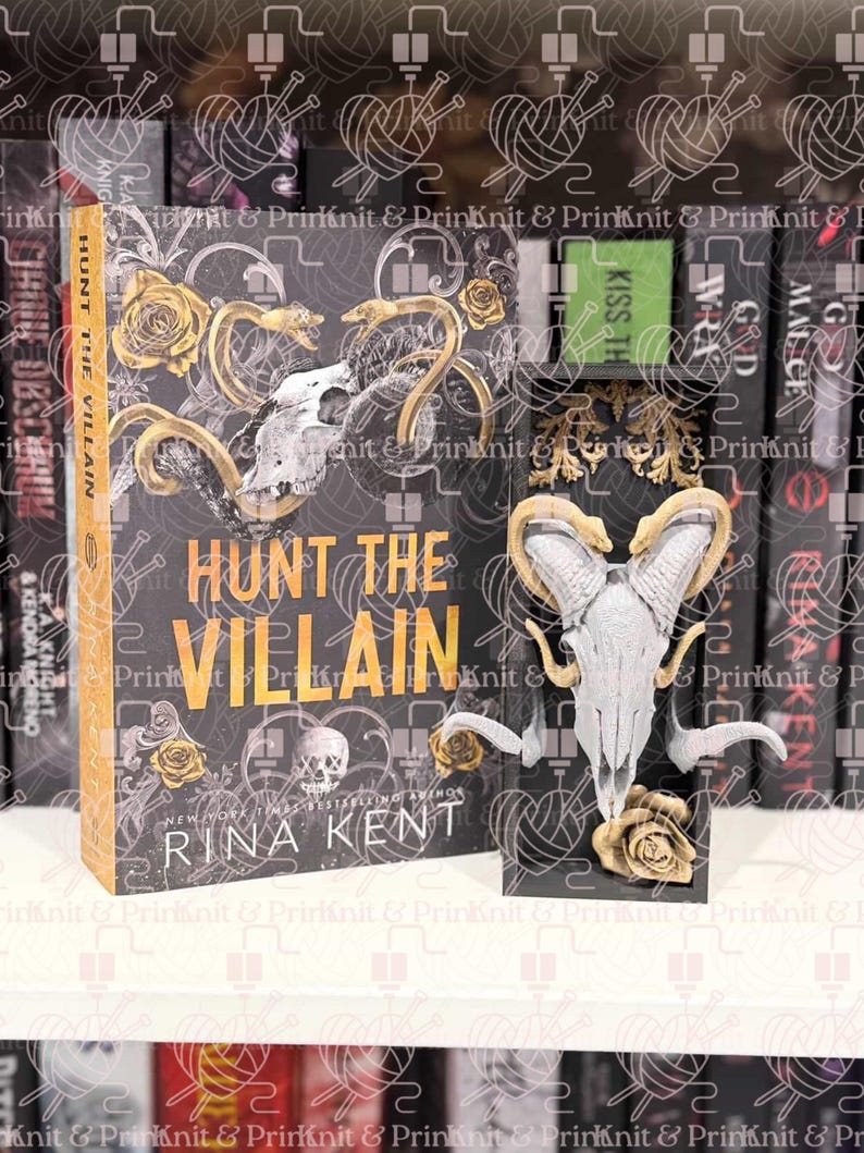 May include: A book titled "HUNT THE VILLAIN" with a skull and floral design, displayed with a matching skull-shaped bookend. The cover is black with gold lettering and accents. The author's name, Rina Kent, is visible. The book is on a shelf.
