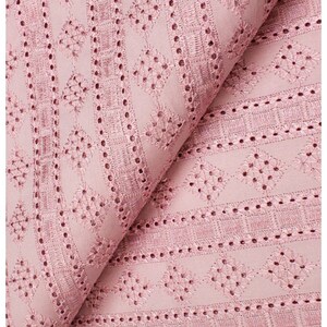 May include: Pink cotton fabric with a delicate embroidered pattern of small flowers and geometric shapes. The fabric has a light, airy feel and is perfect for creating summery garments.