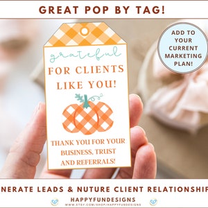 Pu&ograve; includere: Un'etichetta regalo bianca con un bordo a scacchi arancione e bianco. L'etichetta presenta un messaggio scritto a mano che dice "grateful for clients like you!" e un'illustrazione di zucca. Il testo "Thank you for your business, trust and referrals!" &egrave; stampato sotto la zucca.