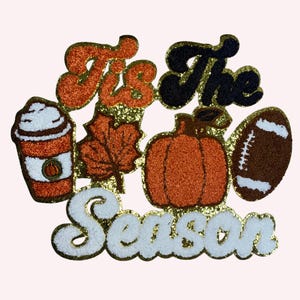 以下が含まれることがあります： 「It's The Season」のテキストが入った、キラキラ光る秋をテーマにしたデザイン。コーヒーカップ、カエデの葉、カボチャ、フットボールが特徴です。オレンジ、茶色、黒、白、金色の色を使用しています。秋の装飾に最適です。
