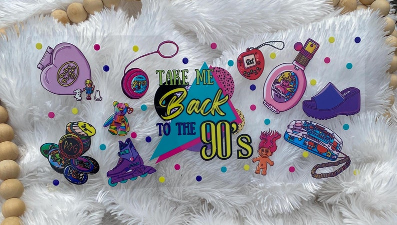 Peut inclure: Ensemble d'autocollants sur le th&egrave;me des ann&eacute;es 90, comprenant un Polly Pocket, un yo-yo, un Tamagotchi, un flacon de parfum, une sandale &agrave; plateforme, un patin &agrave; roulettes, une poup&eacute;e troll et des POGs. Le texte "Take Me Back to the 90's" est &eacute;galement inclus.