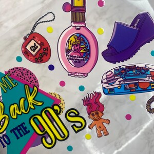 Peut inclure: Ensemble d'autocollants sur le th&egrave;me des ann&eacute;es 90. Comprend un flacon de parfum rose, un jeu portable rouge, une sandale &agrave; plateforme violette, un t&eacute;l&eacute;phone bleu et une poup&eacute;e troll. La phrase "Welcome Back to the 90's" est &eacute;galement pr&eacute;sente.