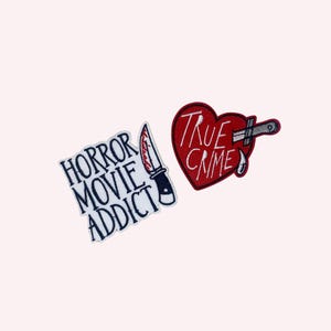 May include: Two embroidered patches with a horror theme. One patch reads "HORROR MOVIE ADDICT" with a knife graphic. The other patch is a red heart with the words "TRUE CRIME" and a knife through it.